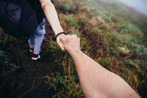 holding hands two person holding hands while walking on grass road human